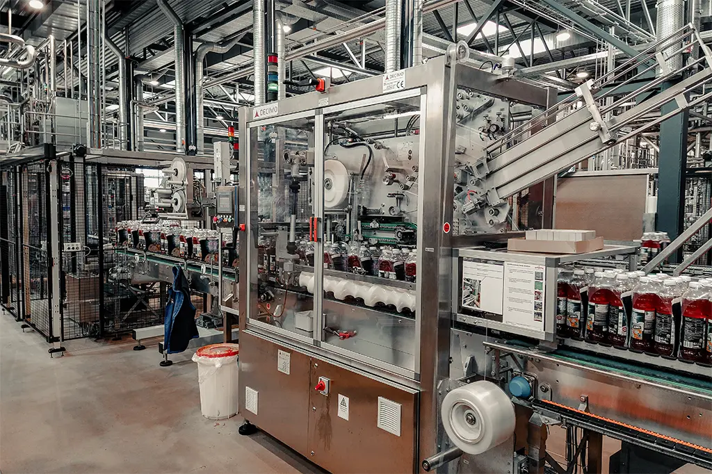 Decimo Srl XHM mechanical handle applicator operating in a tea beverage bottling line